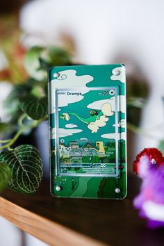 an electronic device sitting on top of a wooden table next to some flowers and plants