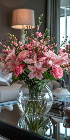 a vase filled with pink flowers sitting on top of a table next to a couch