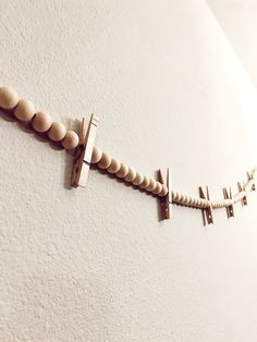 a wall mounted cross on the side of a white wall with wood beads hanging from it's sides