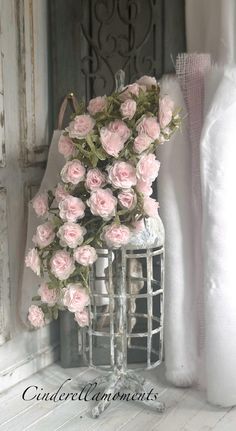 a bunch of pink roses are in a birdcage