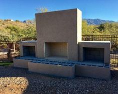 an outdoor fireplace built into the side of a building with rocks and gravel around it