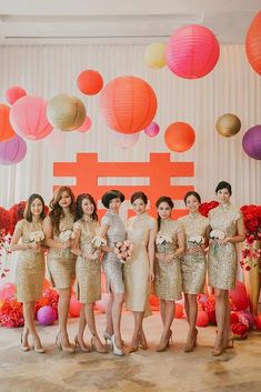 a group of women standing next to each other in front of a wall with paper lanterns