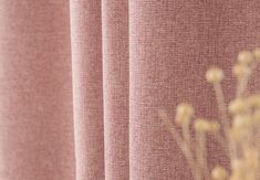 a vase with flowers sitting on top of a window sill next to a curtain