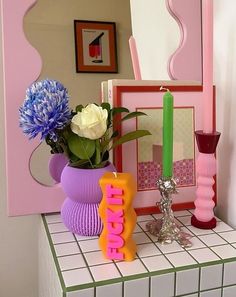 there is a vase with flowers and candles on the counter in front of a mirror