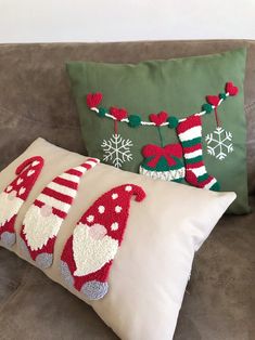 two christmas stockings and one santa clause pillow on a couch