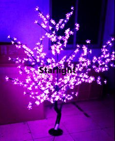 a purple tree is lit up in the dark