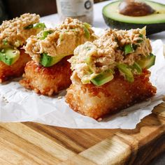 some food is sitting on a cutting board next to an avocado