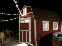 a small red and white shed with lights on the roof