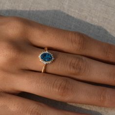 a woman's hand with a ring on it and a blue stone in the middle