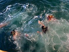 three people swimming in the ocean with their backs turned to the camera and one person standing up