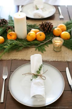 a place setting with oranges and pine cones