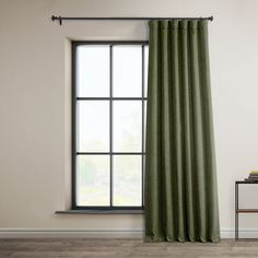 a green curtain hanging from a window next to a table with a book on it