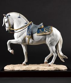 a figurine of a white horse with blue and gold armor on it's back