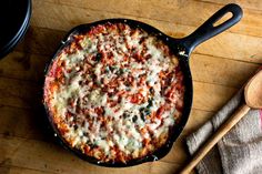 a pizza sitting on top of a pan next to a wooden spoon and spatula