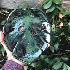 a person holding up a green leaf shaped mask