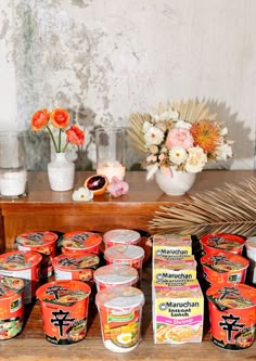 an assortment of yogurt sits on a table next to flowers and vases