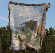 a large tapestry hanging from the side of a wooden pole with trees in the background