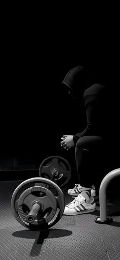 a person squatting on the ground in front of a barbell and weight machine