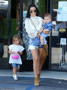 a woman holding a baby while walking down the street with two other women behind her