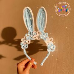 a hand holding up a crocheted bunny ears headband