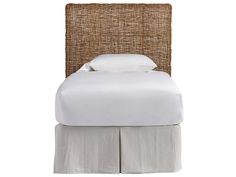 a bed with white linens and pillows on top of the headboard is made out of wicker