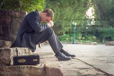 a man in a suit and tie sitting on a stone bench with his hands clasped to his face