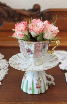 pink roses are in a teacup on a stand