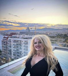 a woman standing on top of a building next to a swimming pool with buildings in the background