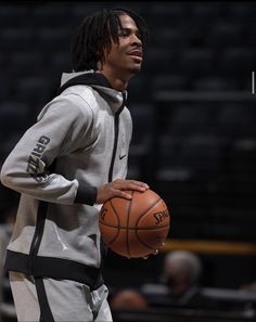 a man holding a basketball in his right hand and wearing a hoodie on the other