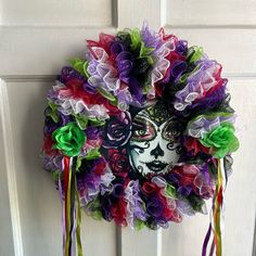 a colorful wreath hanging on the front door decorated with ribbons and flowers, featuring a woman's face