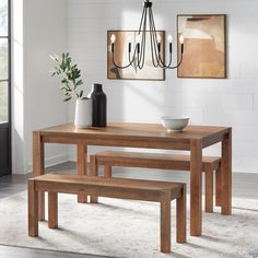 a wooden table with two benches and a vase on the top, in front of a white wall