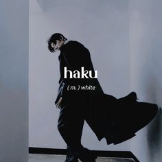 a man in a black suit is standing against a wall with the words haku on it