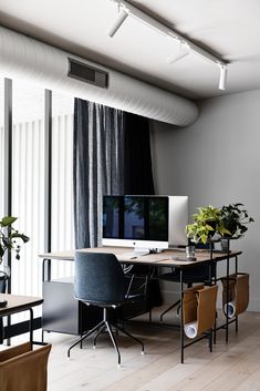 a desk with a computer on top of it in front of a curtained window