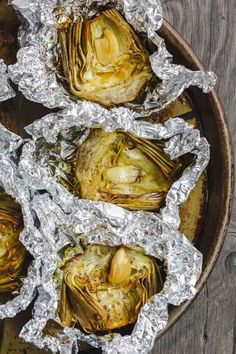 baked artichokes wrapped in aluminum foil on a plate