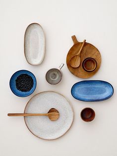 various bowls and spoons are arranged on a white surface with wooden spoons in them