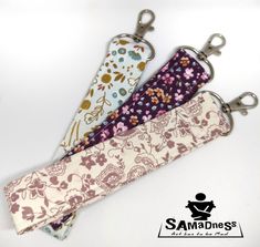 three keychains with different designs on them, one has a flower design and the other has a floral print