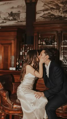 a bride and groom kissing in front of a bar