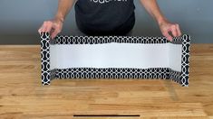 a man is holding up a black and white box on a wooden table with the lid open