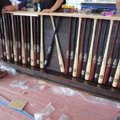 baseball bats are lined up on display in a shop with people looking at them through the window