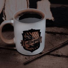 a harry potter coffee mug sitting on top of a wooden table next to a wand