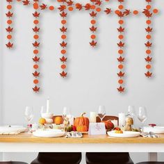 the table is set with plates, glasses and napkins for an autumn themed dinner