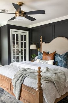 a bedroom with black walls, white bedding and a ceiling fan in the corner