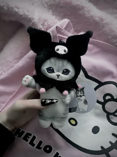 a person holding a hello kitty stuffed animal in their hand and wearing a cat costume