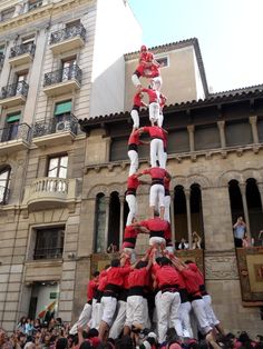 a group of people standing on top of each other in front of a tall building