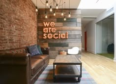 a living room filled with furniture and a wooden sign on the wall above it that says we are social