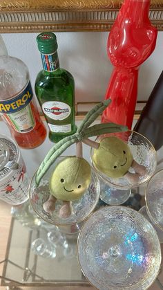 there are some wine glasses and bottles on the counter with stuff animals in them,