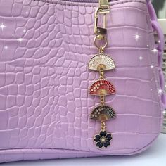 a purple purse with a fan and flower charm hanging from it