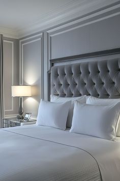 a bed with white sheets and pillows in a bedroom next to two lamps on either side of the bed