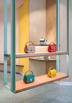 several purses are displayed on shelves in a room with yellow and pink walls,