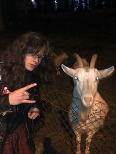 a woman standing next to a goat behind a fence